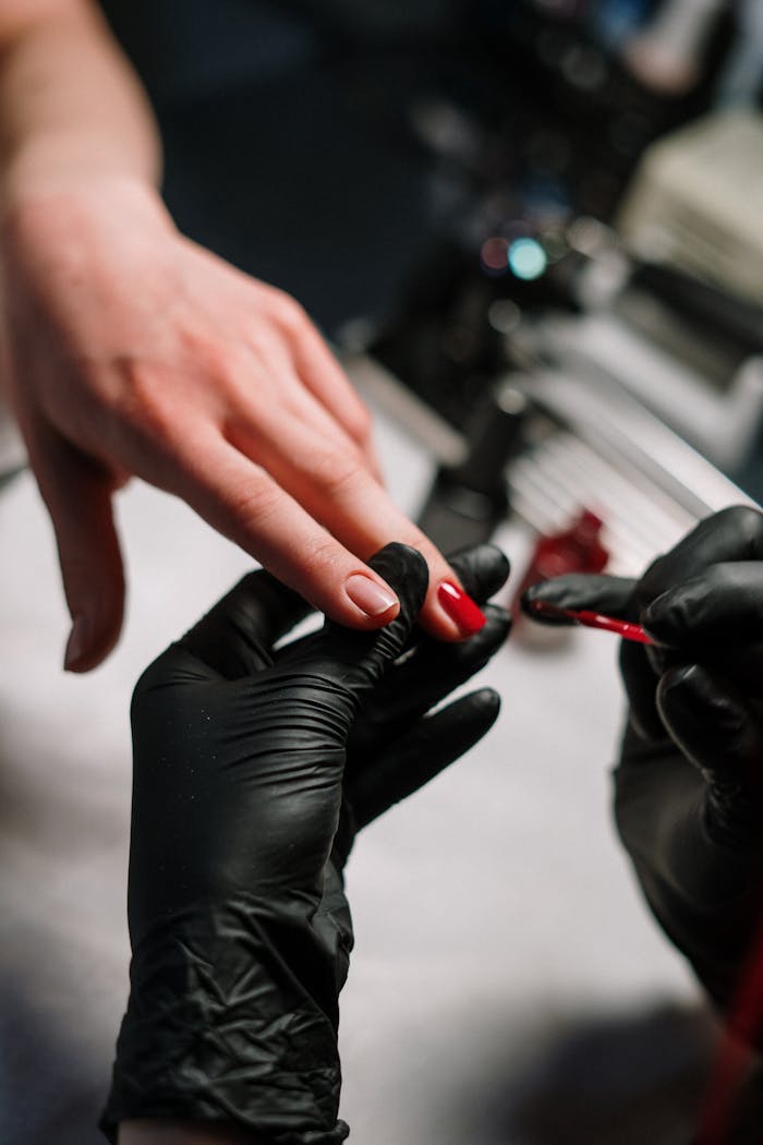 creative-approach-img Close-up of a nail artist applying polish with precision using black gloves in a salon setting.